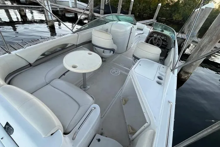 Slide: The Image of 2002 Four Winns 264 Funship boat interior with seating and table, docked by wooden piers. - 20