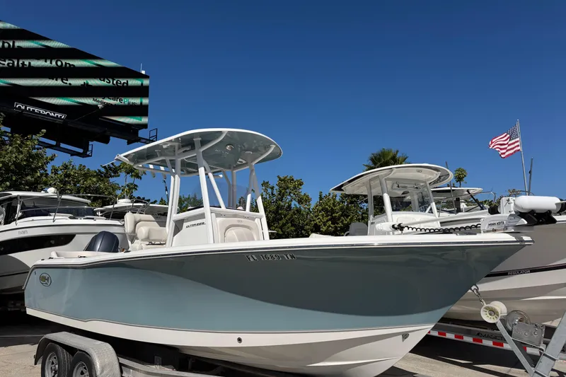 The Image of 2023 Sea Hunt Ultra 229 boat on trailer, displayed outdoors under clear blue sky. - 1