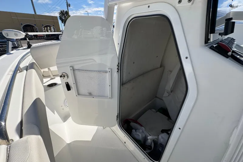 Slide: The Image of 2023 Sea Hunt Ultra 229 boat interior storage compartment with open door, showcasing seating and equipment. - 15