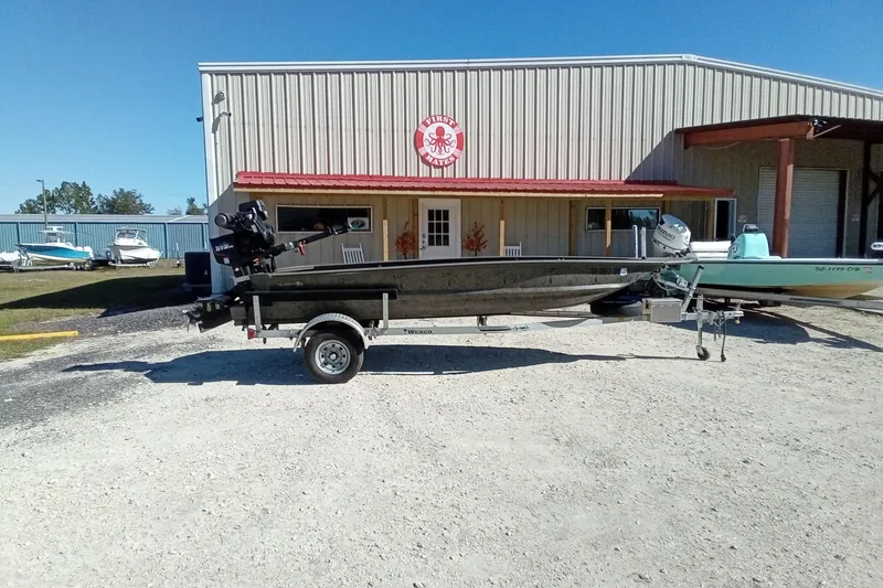 Slide: The Image of 2020 War Eagle 750 Gladiator boat on trailer, parked outside a metal building. - 3