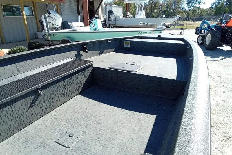 Slide: The Image of 2020 War Eagle 750 Gladiator boat interior with storage compartments, parked outdoors. - 7