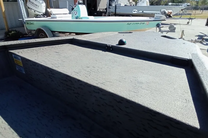 Slide: The Image of 2020 War Eagle 750 Gladiator boat with textured deck, parked near a Bay Craft boat. - 9