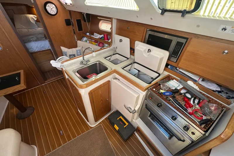 Slide: The Image of Cozy 2005 Catalina 310 yacht kitchen with wood finish, sink, and appliances. - 11