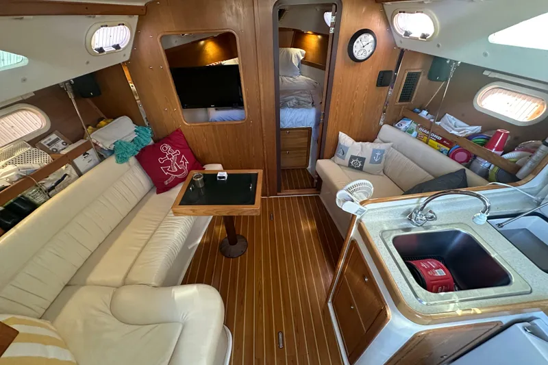 Slide: The Image of Interior of a 2005 Catalina 310 sailboat with cozy seating and wooden finishes. - 12