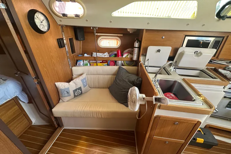 Slide: The Image of Cozy interior of a 2005 Catalina 310 sailboat with seating, kitchen, and nautical decor. - 15