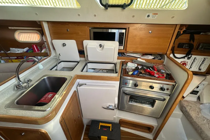 Slide: The Image of Interior of a 2005 Catalina 310 sailboat kitchen with sink, stove, and storage. - 16