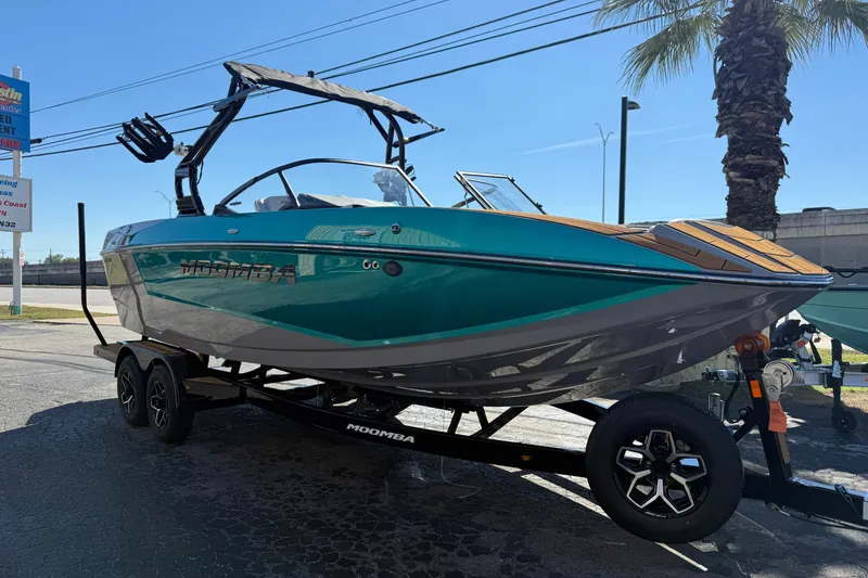 Slide: The Image of 2026 Moomba Mojo boat on trailer, teal and gray design, parked outdoors. - 3