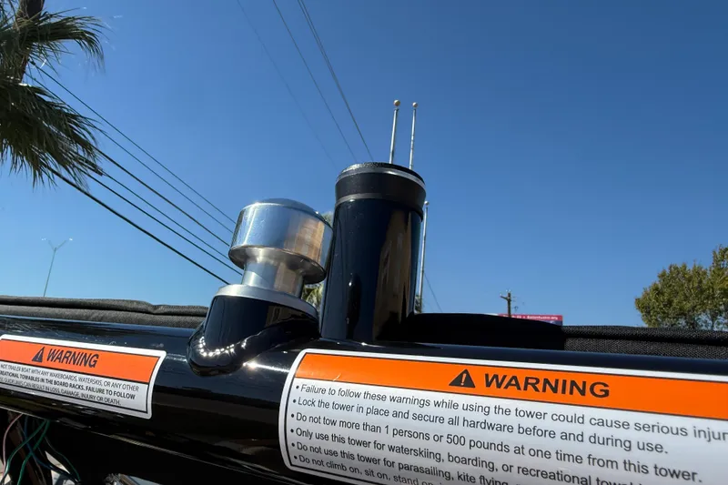 Slide: The Image of 2026 Moomba Mojo boat tower with warning labels under clear blue sky. - 45