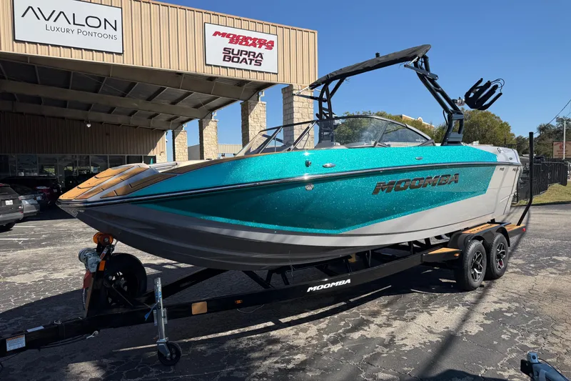 Slide: The Image of 2026 Moomba Mojo boat in teal and gray on a trailer outside a dealership. - 46