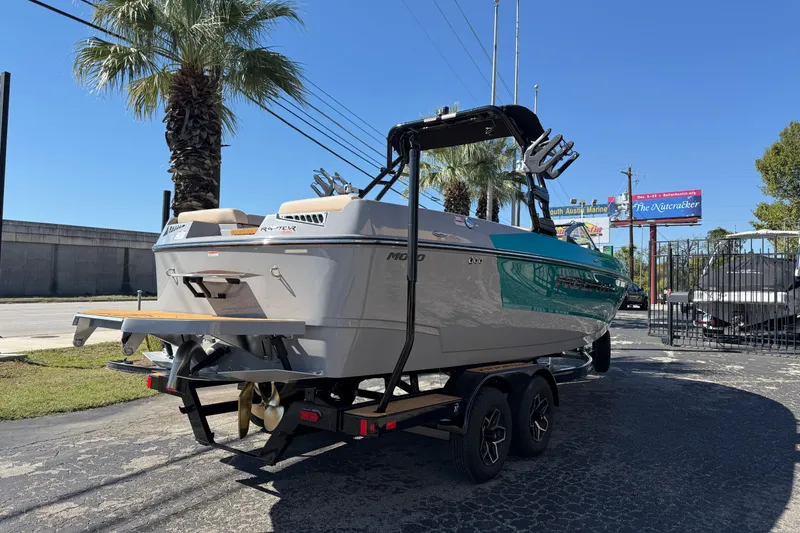 Slide: The Image of 2026 Moomba Mojo boat on trailer, parked outdoors under clear blue sky. - 5