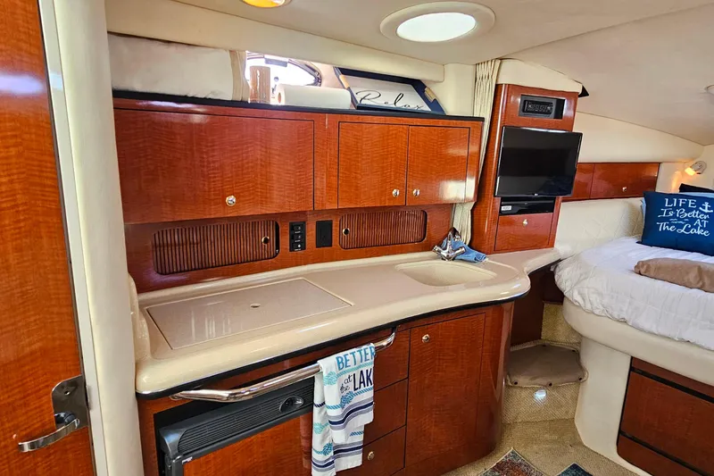 Slide: The Image of 2004 Sea Ray 320 Sundancer interior with wood paneling and compact refrigerator. - 22