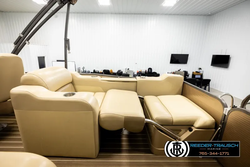 Slide: The Image of 2017 Manitou Oasis SHP boat interior with beige seating in a showroom. - 29