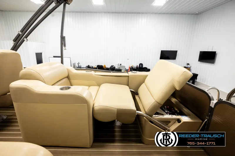 Slide: The Image of 2017 Manitou Oasis SHP boat interior with beige seating and cup holder. - 30
