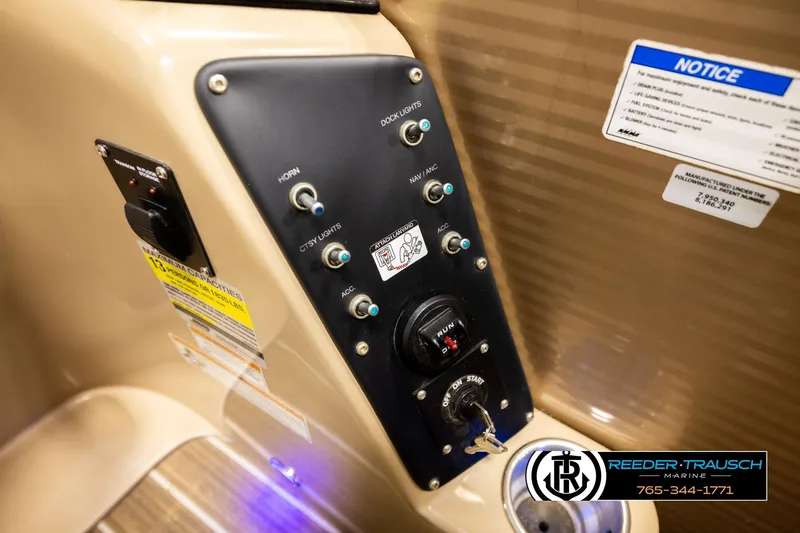 Slide: The Image of Control panel of a 2017 Manitou Oasis SHP boat with various switches and key ignition. - 43