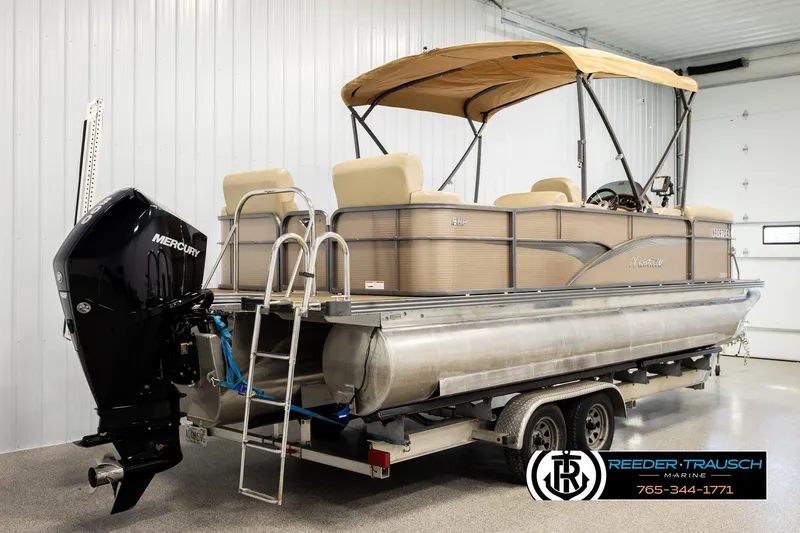 Slide: The Image of 2017 Manitou Oasis SHP pontoon boat with Mercury engine on trailer in indoor setting. - 6