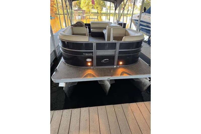 Slide: The Image of 2015 Crest 22 Crest I pontoon boat docked, featuring beige seating and ambient lighting. - 26