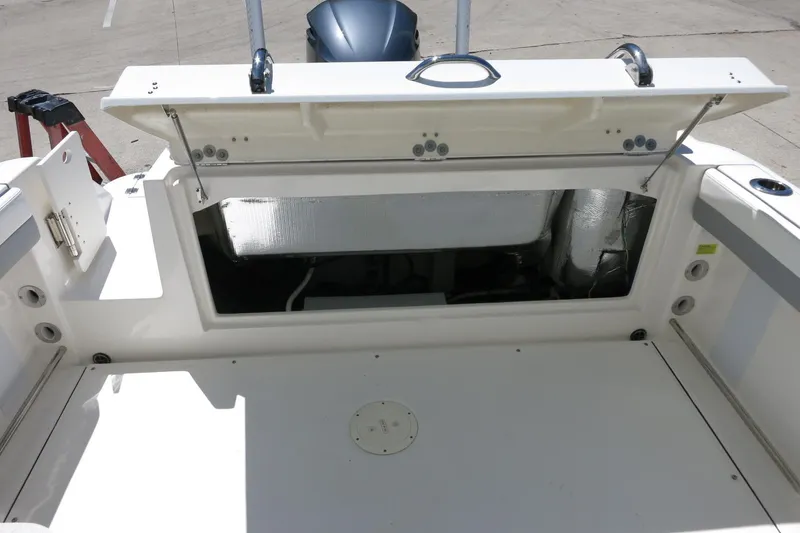 Slide: The Image of 2021 Robalo R247 Dual Console boat storage compartment open, showcasing interior space. - 22