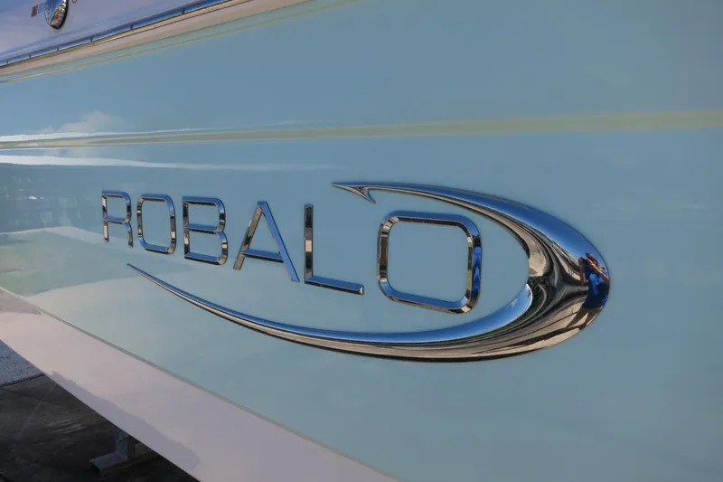 Slide: The Image of 2021 Robalo R247 Dual Console boat logo on light blue hull. - 6