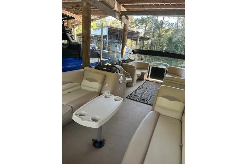 Slide: The Image of 2016 Harris Cruiser 240 interior with beige seating and table, docked under a wooden shelter. - 3