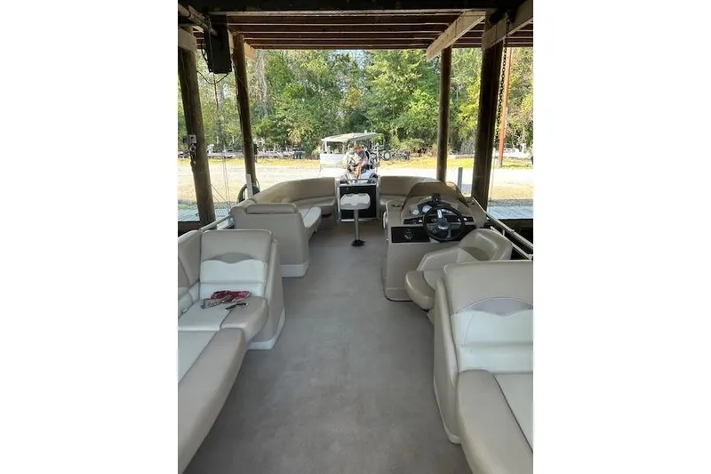 Slide: The Image of 2016 Harris Cruiser 240 pontoon boat interior with beige seating under a wooden canopy. - 5