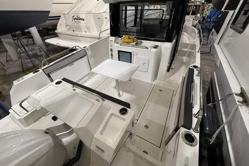 Slide: The Image of 2024 Jeanneau NC Sport 795 Series 2 boat interior with seating and table in a showroom. - 5