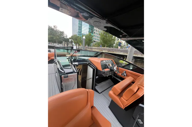 Slide: The Image of 2022 Cruisers Yachts 338 South Beach Edition Bow Rider interior with orange seating and modern dashboard. - 24