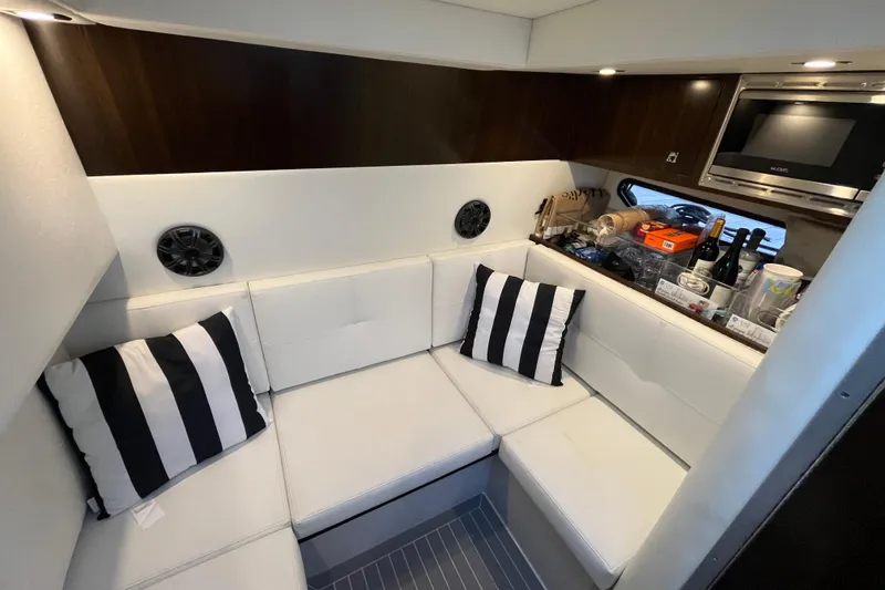 Slide: The Image of 2022 Cruisers Yachts 338 South Beach Edition interior with white seating and striped pillows. - 41