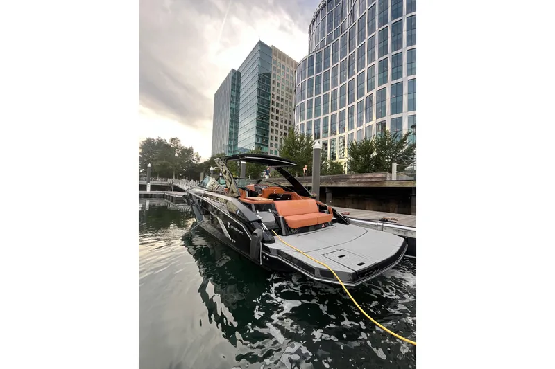Slide: The Image of 2022 Cruisers Yachts 338 South Beach Edition Bow Rider docked near modern buildings. - 7
