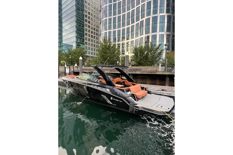 Slide: The Image of 2022 Cruisers Yachts 338 South Beach Edition Bow Rider docked near modern buildings. - 6