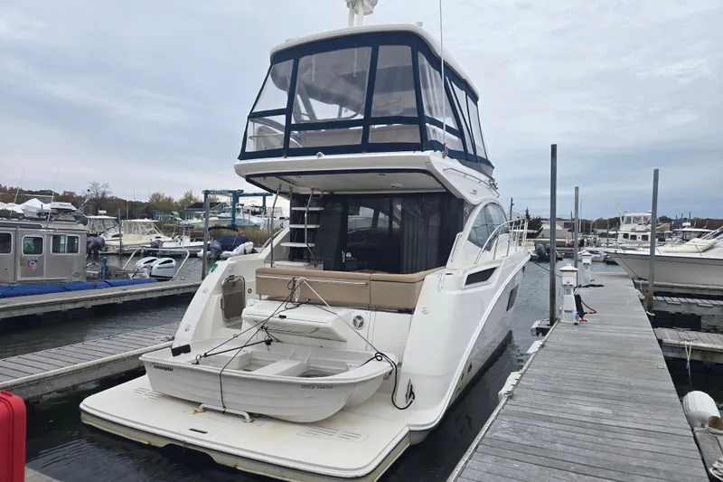 Slide: The Image of 2016 Sea Ray 400 Fly yacht docked at marina, featuring flybridge and tender boat. - 22