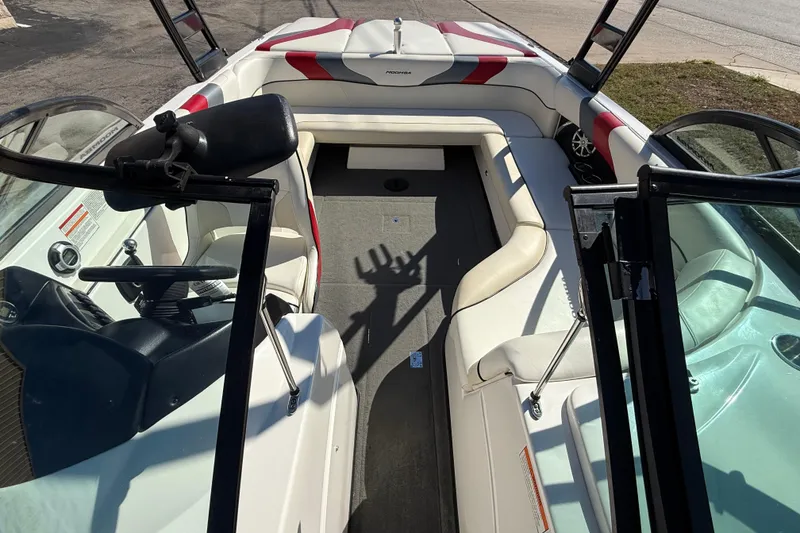 Slide: The Image of 2012 Moomba Mobius LSV boat interior with white and red seating, open windshield, and steering wheel. - 10