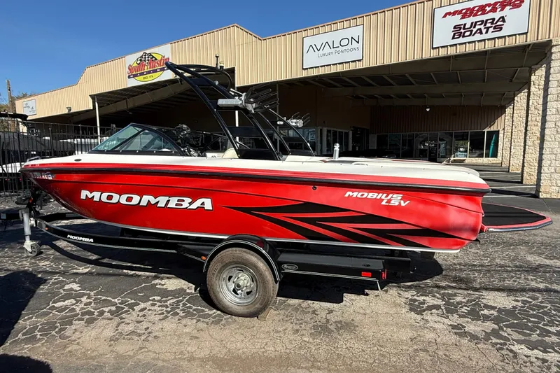 Slide: The Image of 2012 Moomba Mobius LSV boat in red, parked outside a dealership. - 3