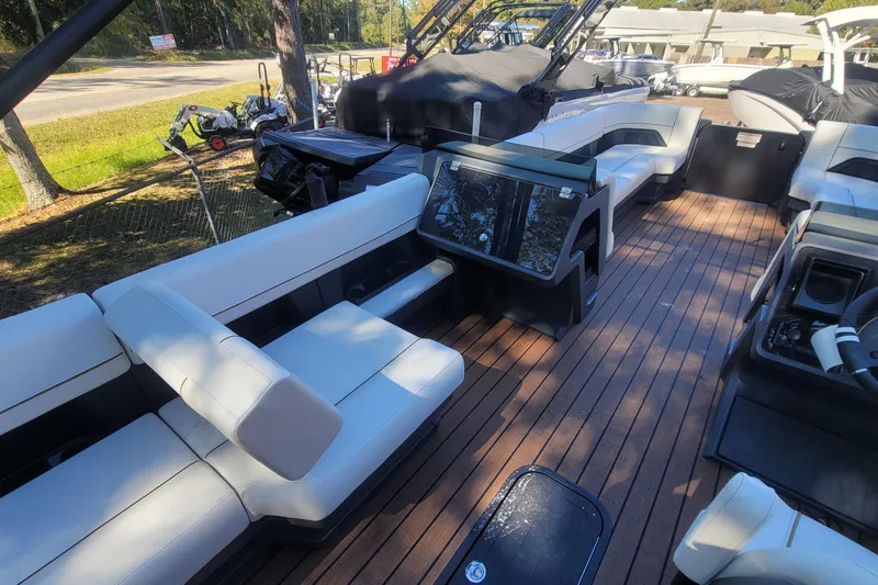 Slide: The Image of 2025 Manitou Explore 26 Switchback boat interior with sleek seating and wooden deck. - 15