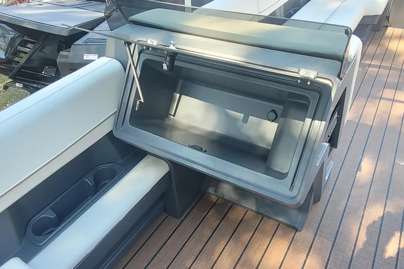 Slide: The Image of Open storage compartment on 2025 Manitou Explore 26 Switchback boat with cushioned seating. - 17