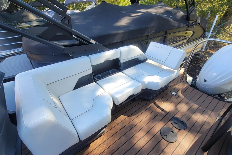 Slide: The Image of 2025 Manitou Explore 26 Switchback boat with white seating on a wooden deck. - 19
