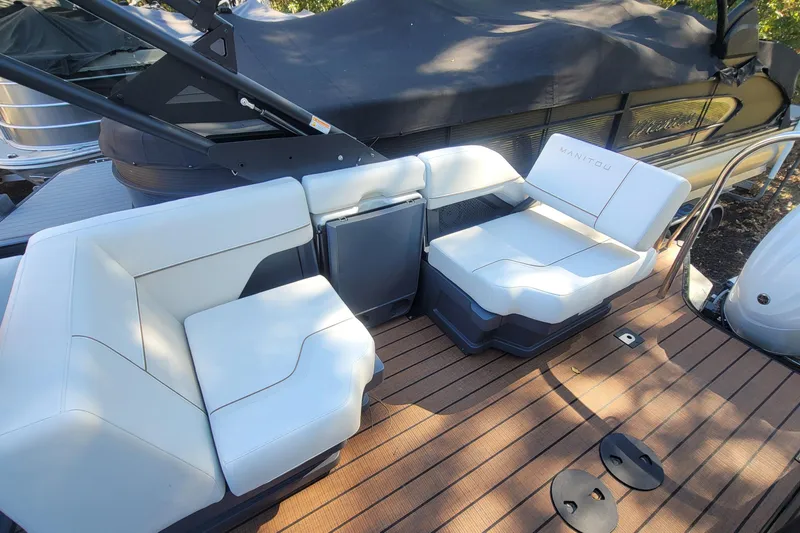 Slide: The Image of 2025 Manitou Explore 26 Switchback boat interior with white seating on wooden deck. - 20