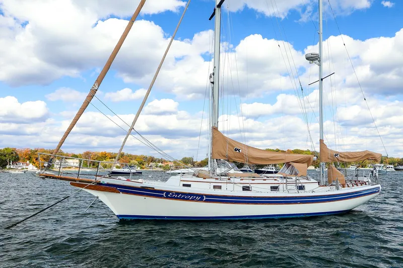 The Image of 1985 Bayfield 40 yacht sailing on a scenic lake under a partly cloudy sky. - 0