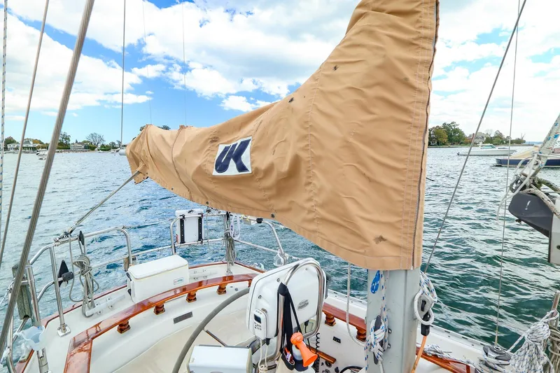 Slide: The Image of 1985 Bayfield 40 sailboat deck with tan sail cover, on calm waters under blue sky. - 14