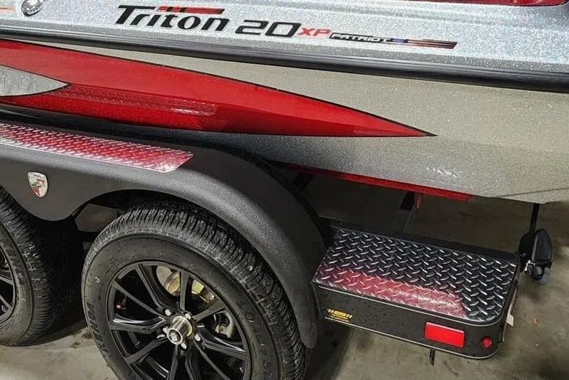 Slide: The Image of 2026 Triton 20XP Patriot boat trailer with black wheels and red accents. - 7