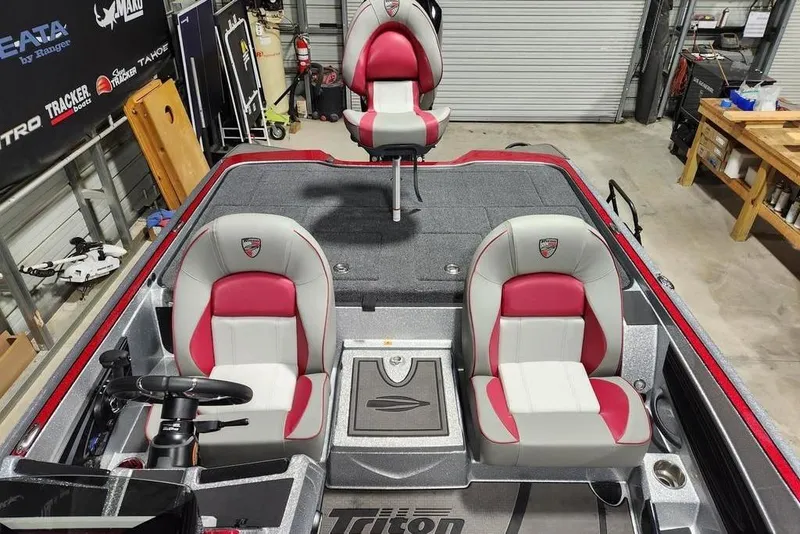 Slide: The Image of 2026 Triton 20XP Patriot boat interior with red and gray seating in a garage setting. - 9