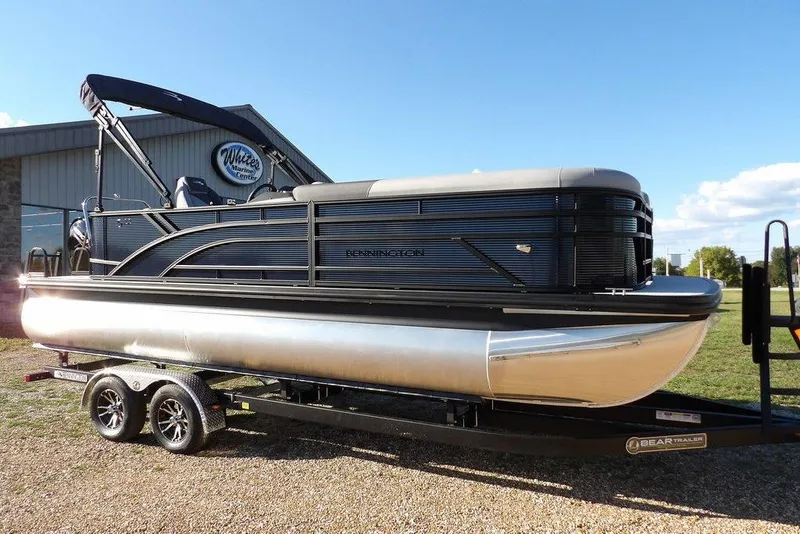 Slide: The Image of 2026 Bennington S L-Bench 22 SL pontoon boat on trailer, parked outdoors. - 1