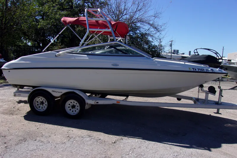 The Image of 2002 Crownline 202 BR boat on trailer with red canopy, parked outdoors. - 1