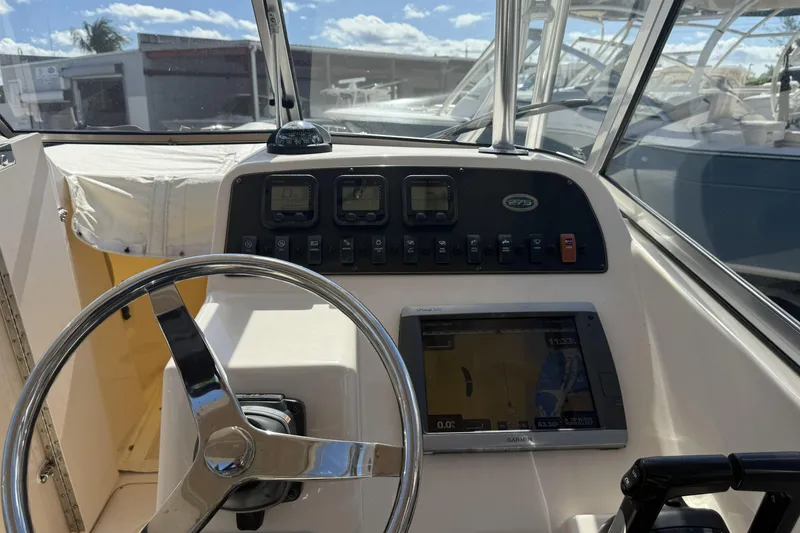 Slide: The Image of 2014 Grady-White Freedom 275 boat dashboard with steering wheel and navigation controls. - 14