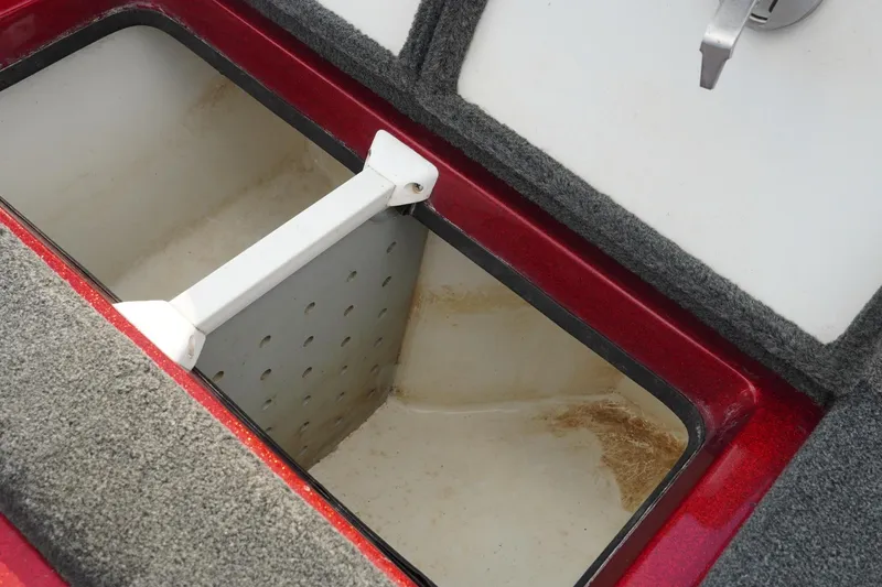 Slide: The Image of Open storage compartment in 2011 Ranger Z119 boat, featuring red trim and carpeted edges. - 26