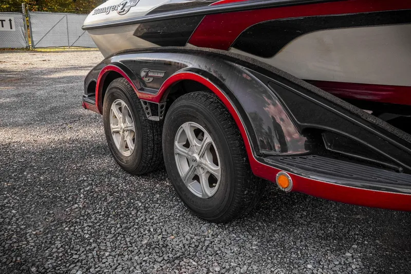 Slide: The Image of 2011 Ranger Z119 boat trailer with dual wheels on gravel surface. - 32