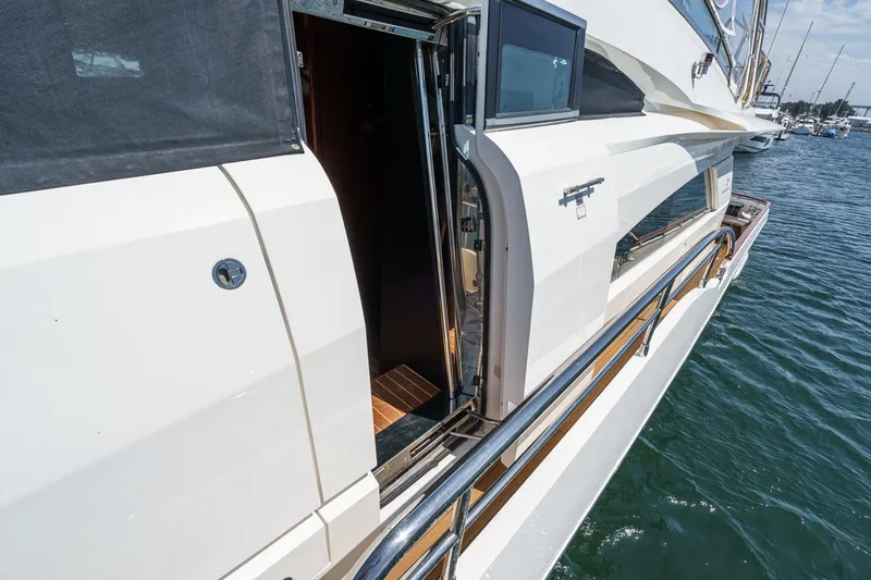 Slide: The Image of 2006 Fairline 74 Custom yacht side view with open door, docked on water. - 23