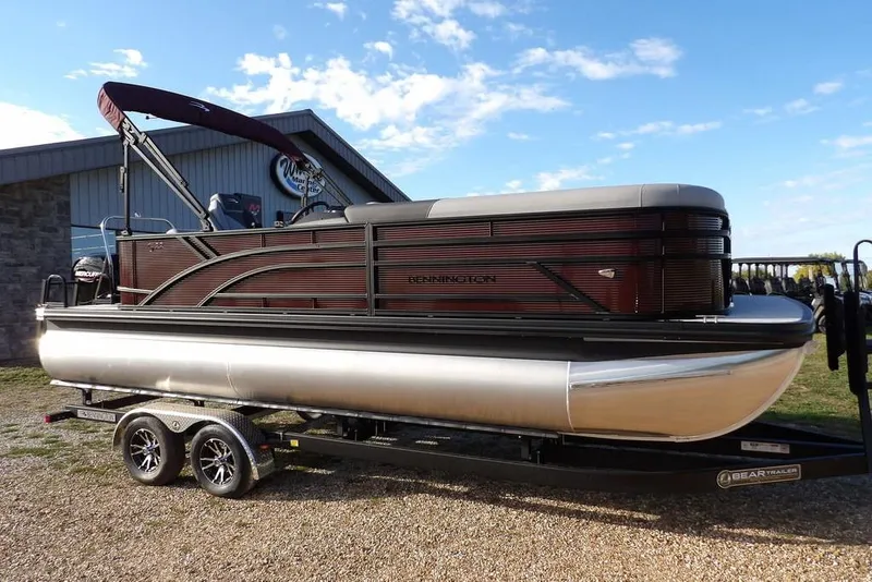 The Image of 2026 Bennington S L-Bench 22 SL pontoon boat on trailer, parked outdoors. - 1