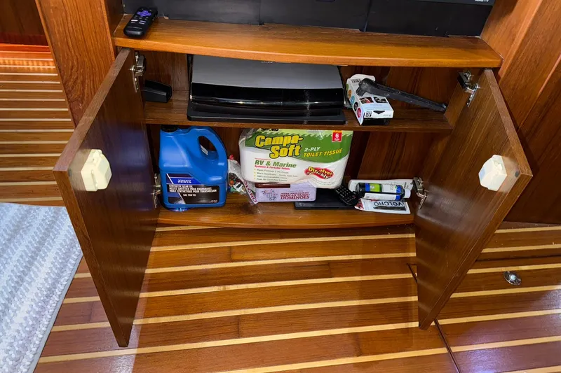 Slide: The Image of Open wooden cabinet on Tiara Yachts 4500 Sovran, 2011, with various stored items. - 48