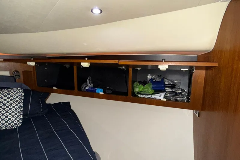 Slide: The Image of 2011 Tiara Yachts 4500 Sovran cabin storage with open compartments and bedding. - 53