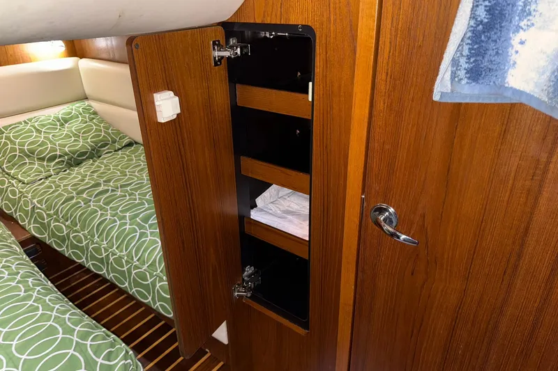 Slide: The Image of Interior of 2011 Tiara Yachts 4500 Sovran with open wooden cabinet and green-patterned bedding. - 71